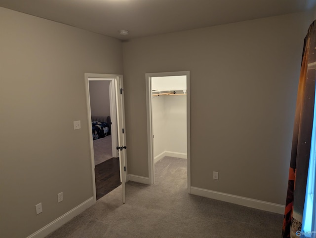 unfurnished bedroom featuring carpet floors, a closet, and a spacious closet