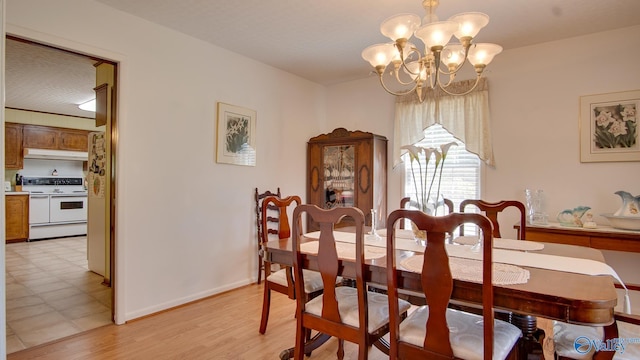 dining area featuring light wood-type flooring, an inviting chandelier, and baseboards