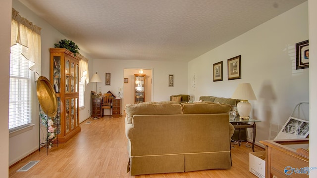living room with visible vents, light wood-style flooring, and baseboards