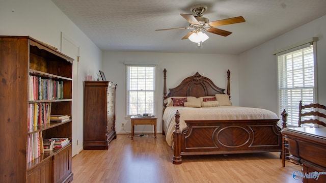 bedroom with light wood finished floors, ceiling fan, multiple windows, and baseboards