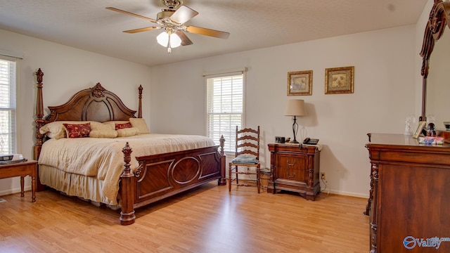 bedroom with light wood finished floors, multiple windows, baseboards, and a ceiling fan