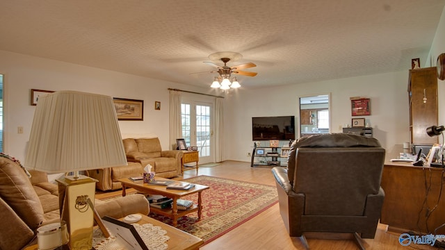 living area featuring light wood finished floors, a textured ceiling, ceiling fan, and plenty of natural light