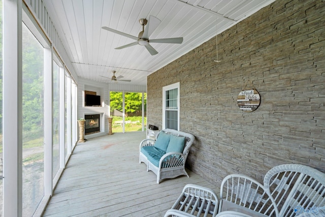 wooden terrace featuring a lit fireplace and a ceiling fan