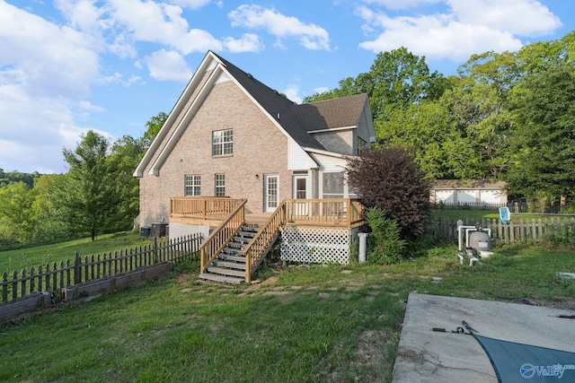 rear view of house featuring a deck, brick siding, a fenced backyard, a yard, and stairs
