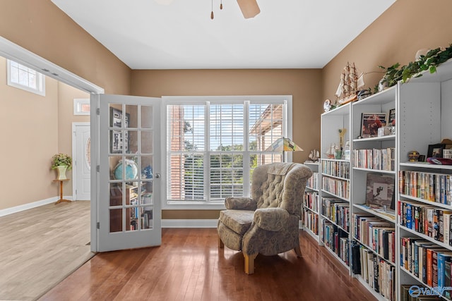 sitting room with baseboards, ceiling fan, and wood finished floors