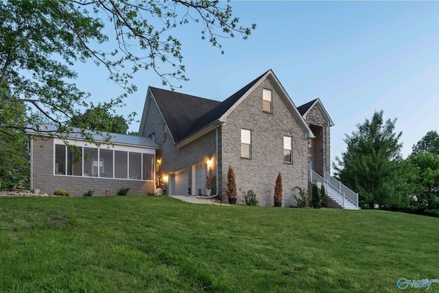 rear view of house featuring a sunroom, a garage, a lawn, and stairs