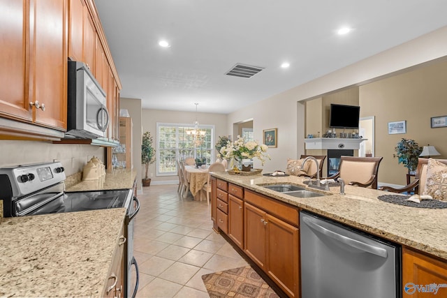 kitchen featuring brown cabinets, a chandelier, appliances with stainless steel finishes, and a sink