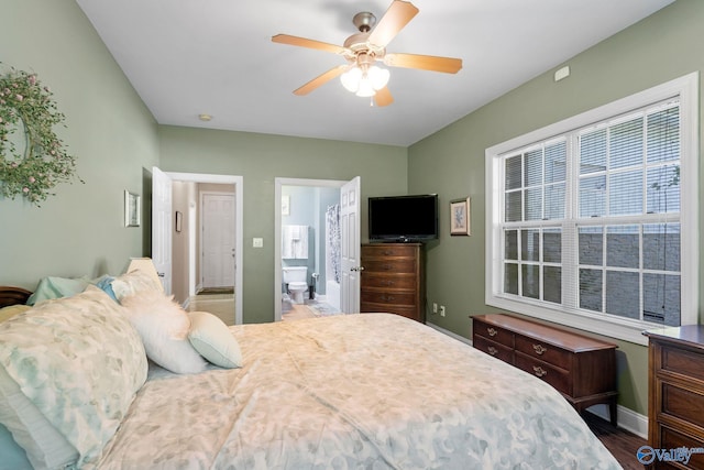 bedroom with baseboards, ceiling fan, wood finished floors, and connected bathroom