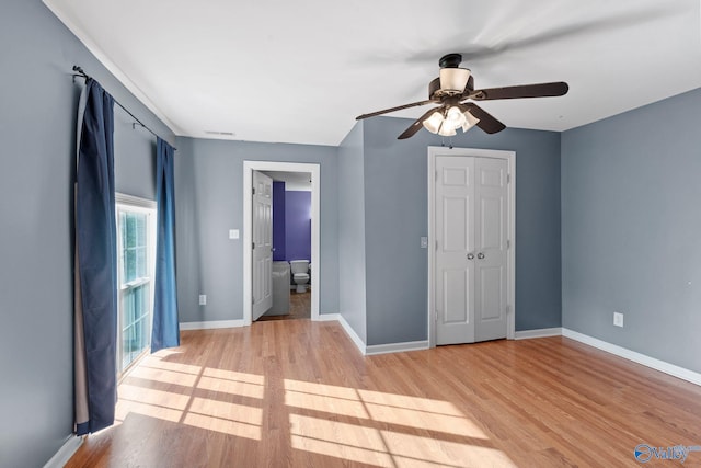 unfurnished bedroom with a ceiling fan, visible vents, baseboards, connected bathroom, and light wood-style flooring