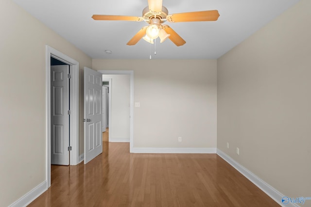 empty room with a ceiling fan, baseboards, and wood finished floors