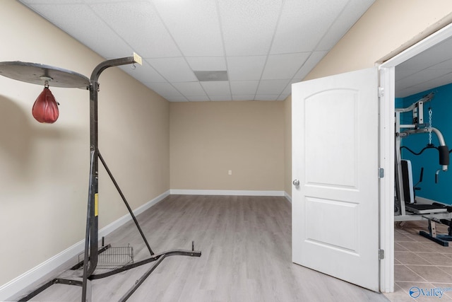 workout room with baseboards, a drop ceiling, and wood finished floors