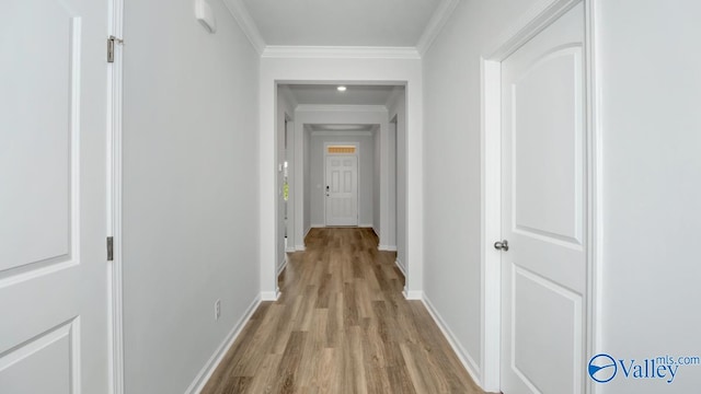 corridor with light wood-type flooring and ornamental molding