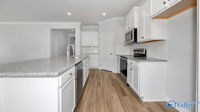 kitchen with white cabinets, appliances with stainless steel finishes, light wood-type flooring, and a center island with sink