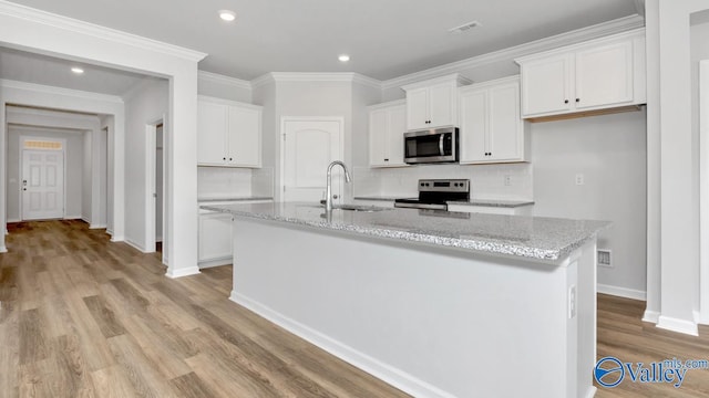 kitchen featuring light stone countertops, sink, stainless steel appliances, a center island with sink, and white cabinets