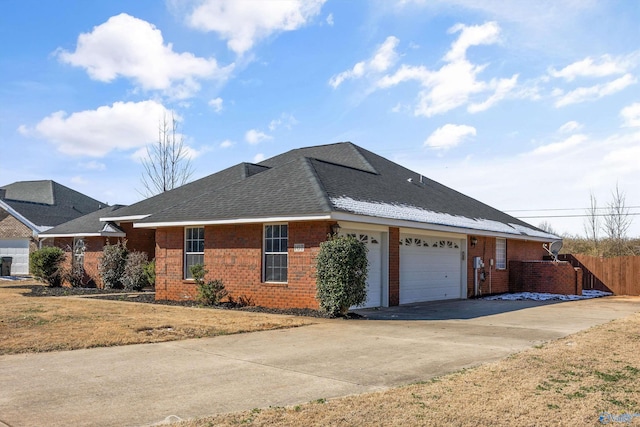 view of side of home featuring a garage, concrete driveway, brick siding, and fence