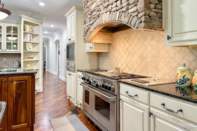 kitchen with dark wood finished floors, open shelves, arched walkways, decorative backsplash, and range with two ovens