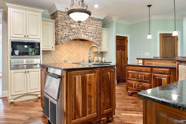 kitchen with black microwave, light wood-style flooring, cream cabinets, and a sink