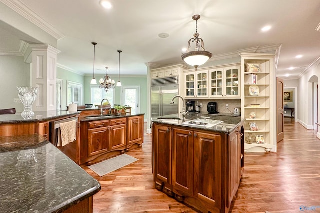 kitchen with open shelves, a sink, light wood-type flooring, a center island with sink, and appliances with stainless steel finishes