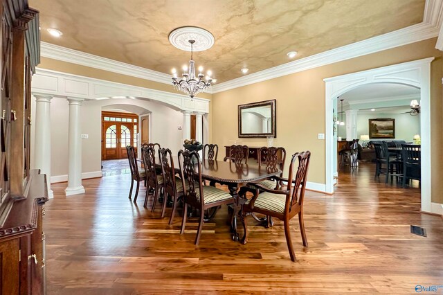 dining space featuring ornamental molding, decorative columns, hardwood / wood-style floors, and a chandelier