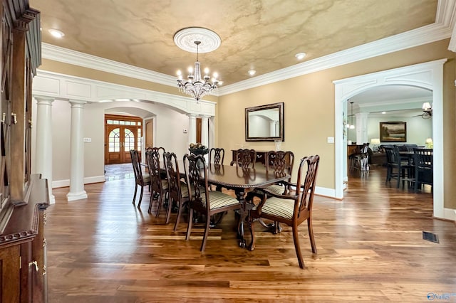 dining space featuring arched walkways, wood finished floors, and ornate columns