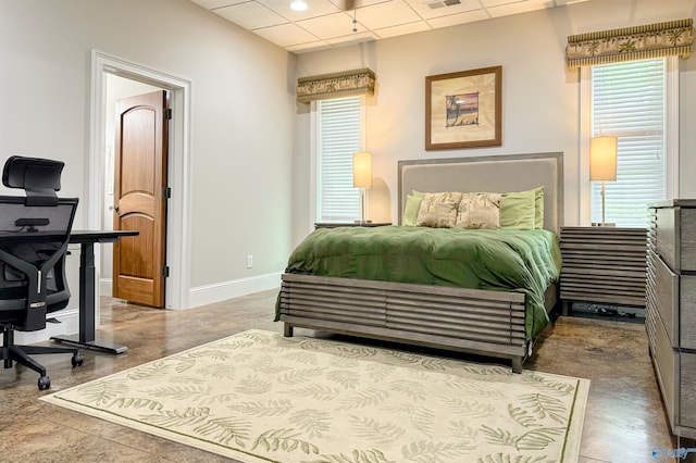 bedroom featuring baseboards, visible vents, multiple windows, and a drop ceiling