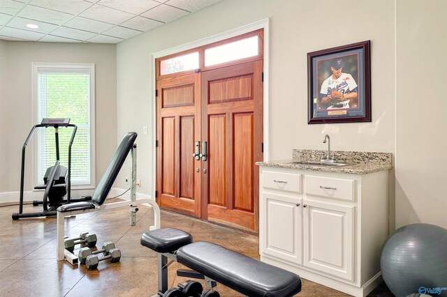 exercise area featuring light tile patterned flooring, sink, and a paneled ceiling