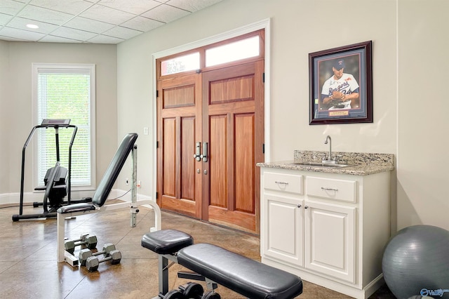 workout area featuring a wealth of natural light, baseboards, a sink, and wet bar