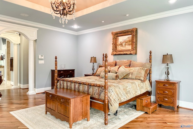 bedroom with arched walkways, decorative columns, baseboards, wood finished floors, and crown molding