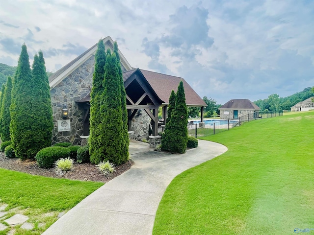 view of property's community with fence, a yard, a gazebo, and a swimming pool