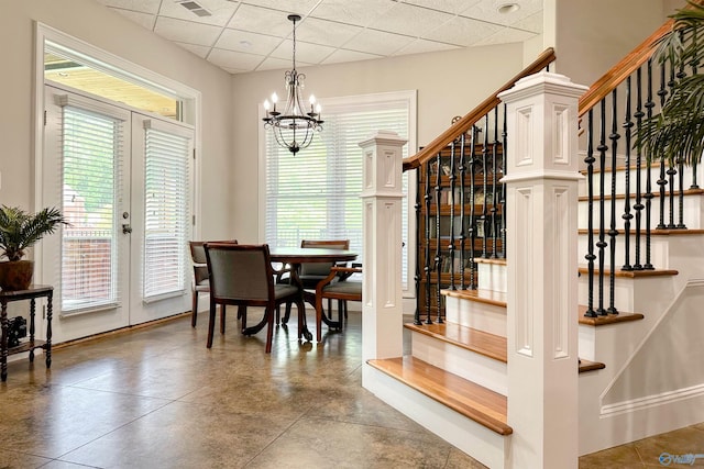 dining room with plenty of natural light, a drop ceiling, stairs, and an inviting chandelier