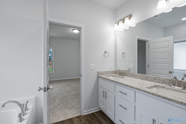 bathroom with double vanity, wood-type flooring, and a bath