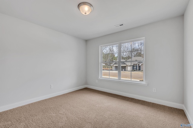 spare room featuring carpet flooring, visible vents, and baseboards