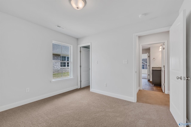 unfurnished bedroom with carpet flooring, visible vents, and baseboards