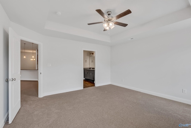 unfurnished bedroom with baseboards, a tray ceiling, and dark carpet