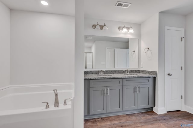 full bathroom featuring a bath, visible vents, a sink, and wood finished floors