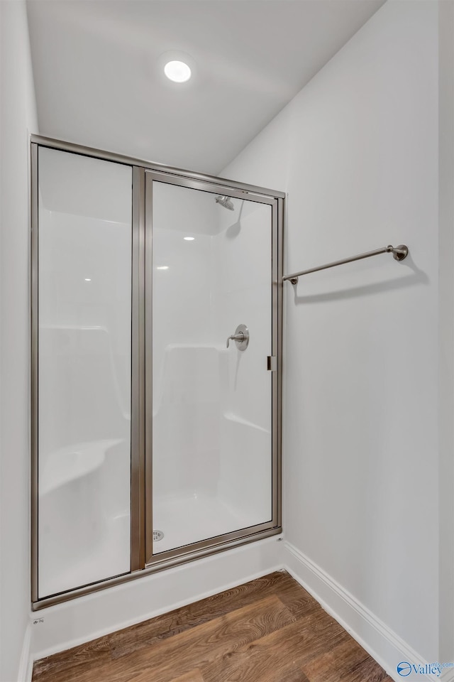 full bathroom with a shower stall, baseboards, and wood finished floors