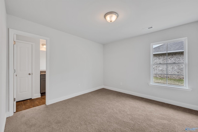 unfurnished room featuring baseboards, visible vents, and dark colored carpet