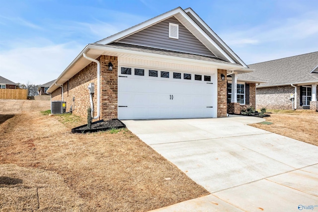 view of front of house featuring a garage, driveway, brick siding, and central AC