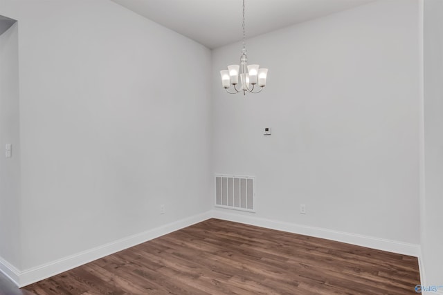 spare room featuring dark wood-style flooring, visible vents, and baseboards