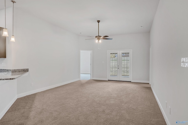 carpeted empty room featuring french doors, a ceiling fan, and baseboards