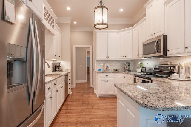 kitchen featuring light wood-type flooring, sink, white cabinets, appliances with stainless steel finishes, and decorative light fixtures