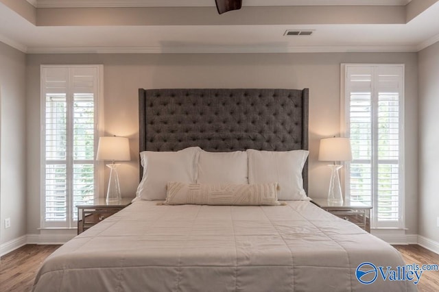 bedroom featuring multiple windows, hardwood / wood-style flooring, and crown molding