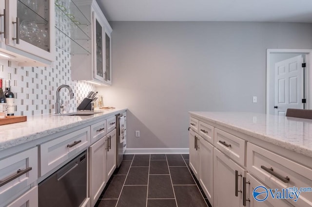 kitchen with light stone countertops, white cabinetry, sink, and tasteful backsplash