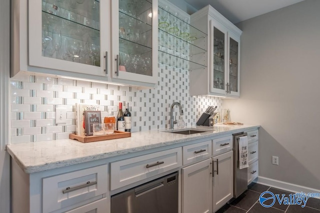 bar with light stone countertops, backsplash, sink, and white cabinetry