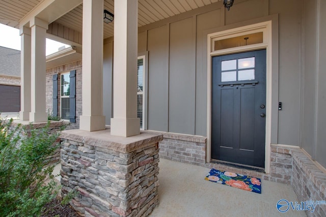 entrance to property featuring board and batten siding, brick siding, and covered porch