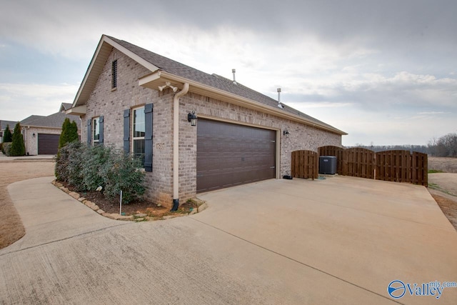 view of home's exterior featuring concrete driveway, a gate, and brick siding