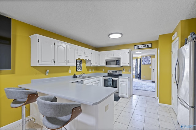 328 Shadow Pointe Dr SW, Decatur, AL 35601 - kitchen with appliances with stainless steel finishes, a peninsula, white cabinetry, light countertops, and light tile patterned floors