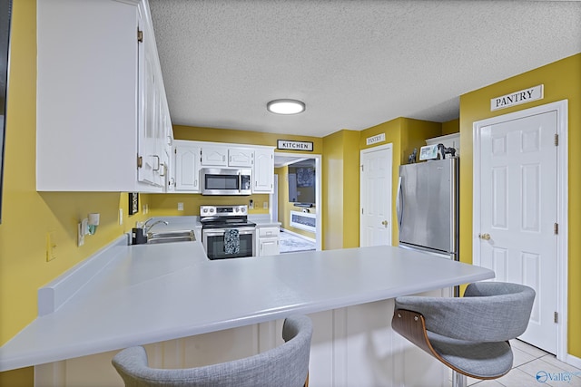 328 Shadow Pointe Dr SW, Decatur, AL 35601 - kitchen with stainless steel appliances, a peninsula, white cabinetry, light countertops, and a breakfast bar area