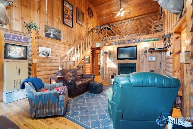 living room featuring hardwood / wood-style floors, log walls, wood ceiling, a fireplace, and high vaulted ceiling