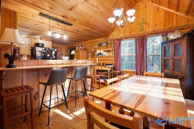 dining area with lofted ceiling, a notable chandelier, wooden walls, light hardwood / wood-style flooring, and wood ceiling